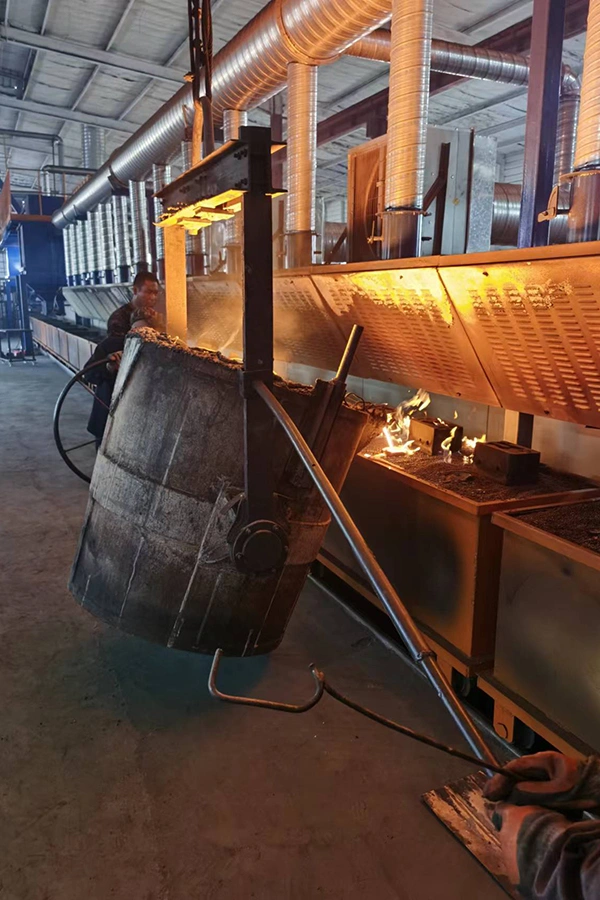 A large metal casting being shaped and processed in a factory setting, showcasing industrial machinery and tools