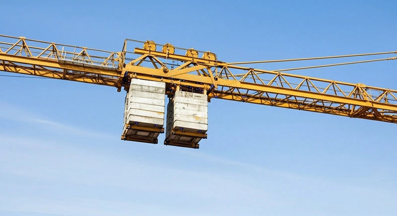 A large yellow crane with counterweights is positioned on top of a building, ready for construction work