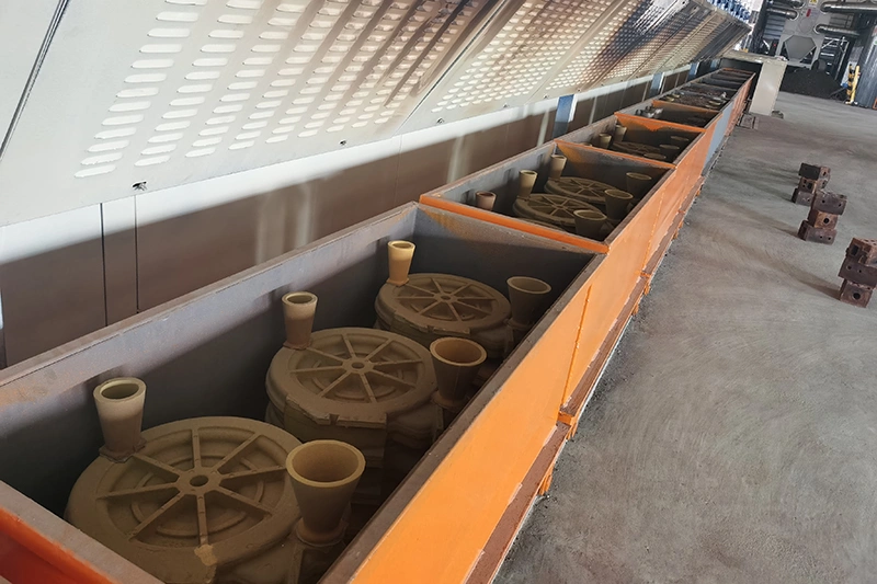 A spacious room featuring large metal pipes and sand casting molds arranged throughout the area