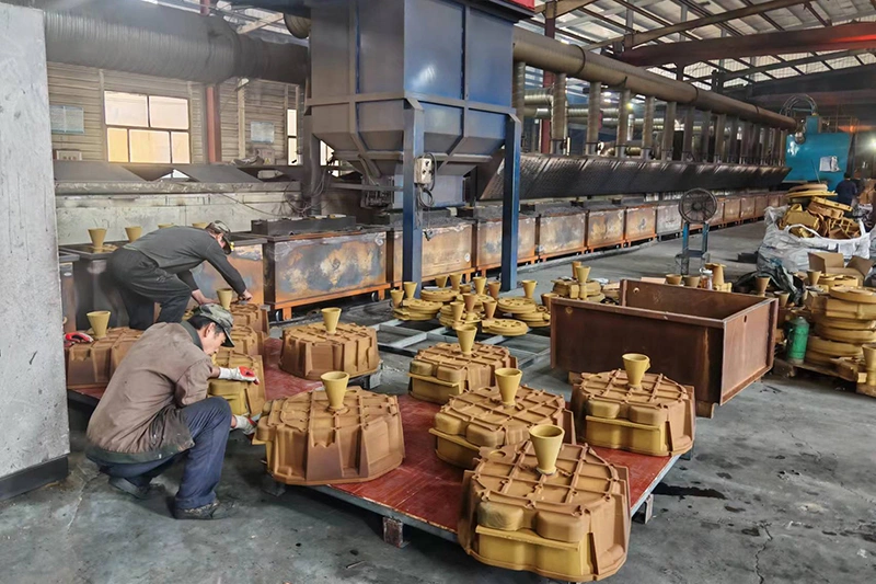 factory scene with workers preparing sand casting molds on a large machine, focused on their tasks